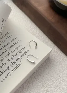 Detail view of S999 sterling silver teardrop hook earrings displayed on a white book