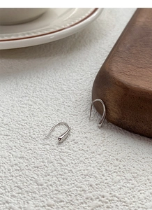 Detail view of S999 sterling silver teardrop hook earrings on a natural wood surface