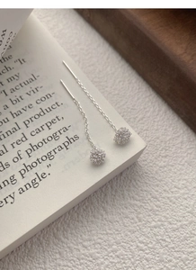 Detail shot of S925 sterling silver dandelion tassel earrings on a vintage book