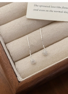 Close-up of S925 sterling silver tassel earrings with hollow bead details in a jewelry box