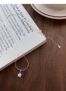 Detail der S925 Sterlingsilber Stern Halskette auf weißem Buch und Holztisch
