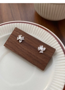 Détail macro de boucles d'oreilles nœud en argent sur support en bois et plat céramique