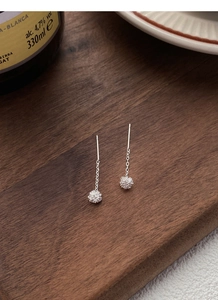 Detail of S925 sterling silver dandelion tassel earrings on dark wooden surface