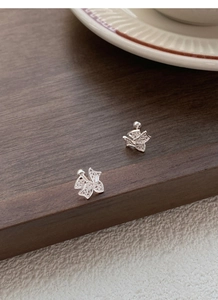Gros plan de boucles d'oreilles nœud en argent avec zircons sur un socle en bois