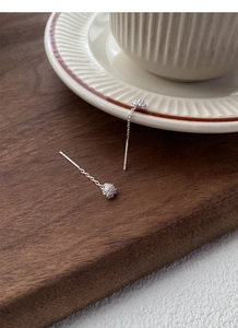 Macro detail of S925 sterling silver dandelion tassel earrings on minimalist display