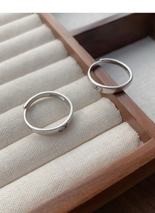Détail de bagues de couple en argent S999 avec gravures fines dans une boîte cadeau