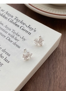 Détail de boucles d'oreilles nœud argenté avec design ajouré sur un fond de livre ouvert