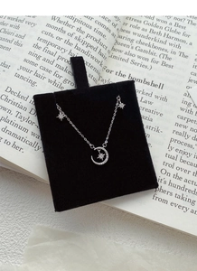 Close-up of S999 sterling silver star and moon necklace with pavé diamonds on display
