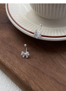 Detailaufnahme von S999 Sterlingsilber Schleifen-Ohrringen auf einem Holztisch