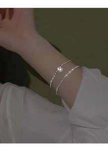 Detail eines doppelreihigen S925 Silberarmbands mit Kugelkette und Herzanhänger