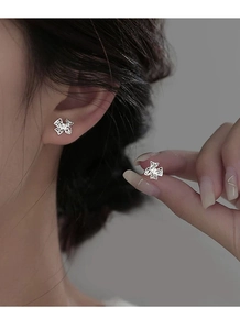 Gros plan détaillé des boucles d'oreilles en argent S999 avec de délicats nœuds papillon évidés