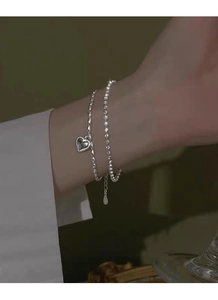 Detailansicht eines zweilagigen S925-Silberarmbands mit runden Perlen und Vintage-Herzanhänger