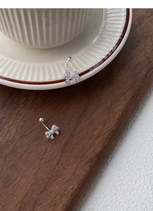 Detailaufnahme von S999 Silber Schleife Ohrringen auf Keramik und Holz Hintergrund