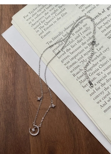 Detailed view of S999 sterling silver moon and star necklace with zircons on wooden background