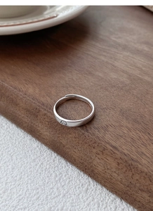 Gros plan d'une bague réglable en argent avec gravure de chiot sur une surface en bois
