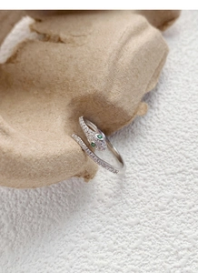Macro shot of silver snake ring with pavé-set zircons and green gemstone eyes