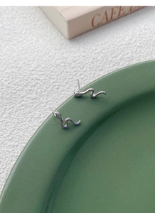 Vista ravvicinata di orecchini a serpente in argento S999 con cristalli su ceramica