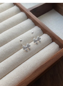 Detailansicht silberner Schleifen-Ohrstecker in einer hölzernen Schmuck-Geschenkbox
