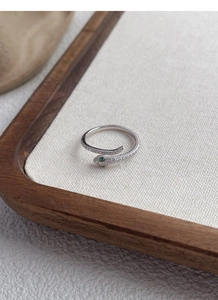 Macro shot of silver snake ring with white zircon pave and green emerald eyes