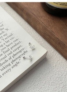 Close-up of small double-layered silver butterfly studs on a vintage book cover
