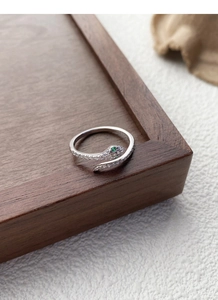 Close-up of S925 silver snake ring with pavé zircons and green gemstone eyes details