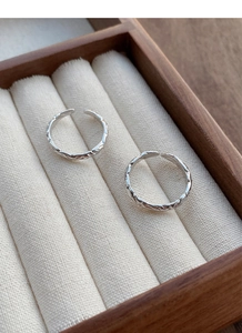 Detail view of 999 sterling silver rings with paper texture in a wooden jewelry box