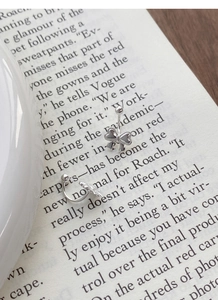 Detailaufnahme von S999 Sterlingsilber Schleifen-Ohrringen auf einem Buch im Vintage-Stil