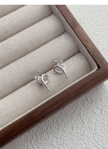 Close-up of S925 silver serpent twist stud earrings with sparkling cubic zirconia inlay