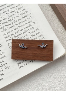 Macro detail of S925 silver snake stud earrings featuring colorful pave-set zircon stones
