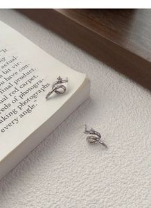 Macro view of a silver snake-shaped stud earring with a sparkling zircon on a book