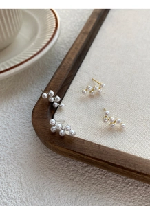 Détail de boucles d'oreilles grappe de perles argentées et dorées sur lin naturel