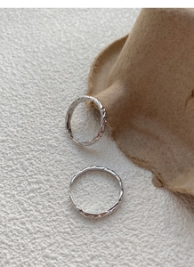 Macro shot of silver couple rings with unique hammered paper texture and open design
