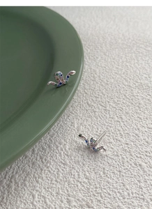 Detailed view of S925 silver snake stud earrings with colorful zircon stones on a ceramic tray