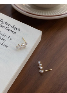 Détail de boucles d'oreilles perles dorées en forme de grappe sur un livre ancien