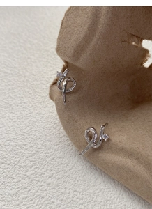 Macro shot of silver twisted snake stud earrings with crystal zircon on kraft card