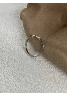 Dettaglio anello in argento 999 con design a nodo di bambù su carta strutturata