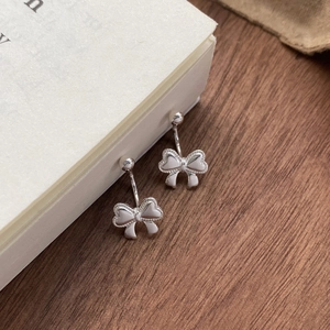 Elegante S999 Silber-Schleifenohrringe mit Perlenkanten auf minimalistischem Buchhintergrund
