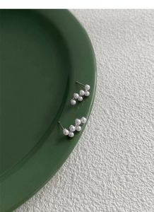 Détail macro du poinçon S925 sur boucles d'oreilles perles sur un plateau en céramique verte