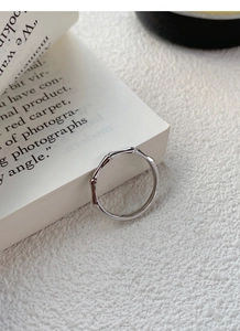 Dettaglio anello in argento 999 con trama a bambù appoggiato su un libro bianco
