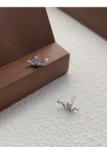 Detail of S925 sterling silver snake stud earrings with colorful zircon stones on wood
