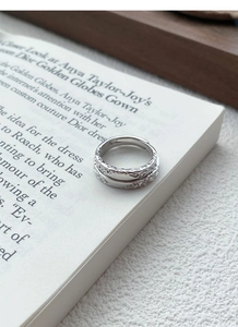 Close-up of S999 sterling silver glacier texture ring resting on an open book