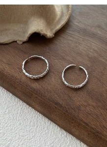 Close-up of 999 sterling silver rings with paper-like texture and open-loop design