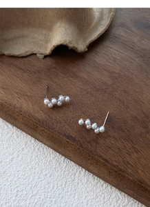 Détail des boucles d'oreilles en argent S925 avec perles en grappe sur support bois