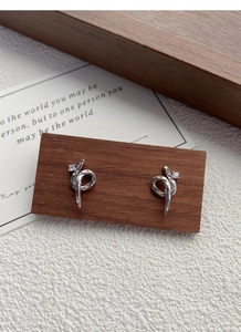 Macro shot of silver snake-shaped knot earrings with sparkling diamond setting