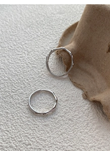 Dettaglio macro di anelli in argento con design a bambù su sfondo rustico di carta
