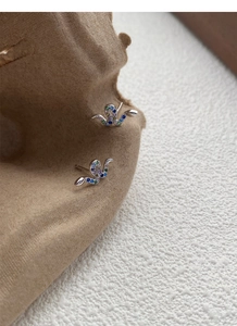 Macro shot of S925 sterling silver snake earrings with colorful zircon stones on brown velvet