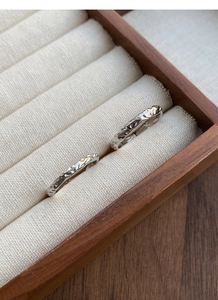 Macro detail of 999 silver rings with irregular crinkle texture in a wooden box