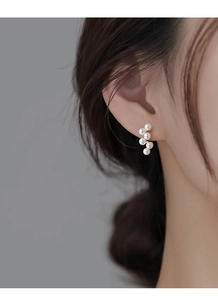 Gros plan d'un modèle portant des boucles d'oreilles grappe en argent S925 avec perles