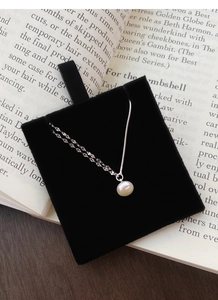 Elegante collana in argento S925 con perla su velluto nero e sfondo di libro d'epoca