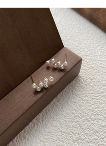 Gros plan détaillé de boucles d'oreilles perles dorées ondulées sur support en bois